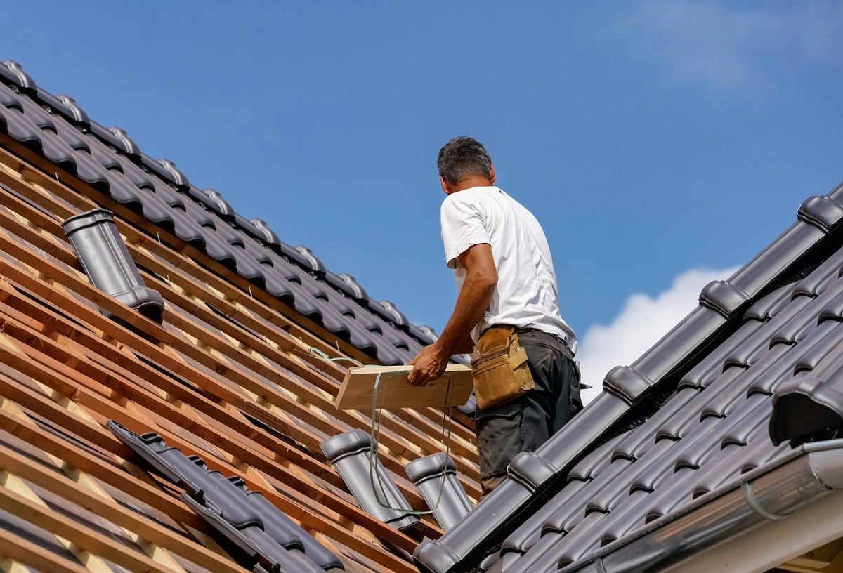 worker replacing the roofing tiles with new ones