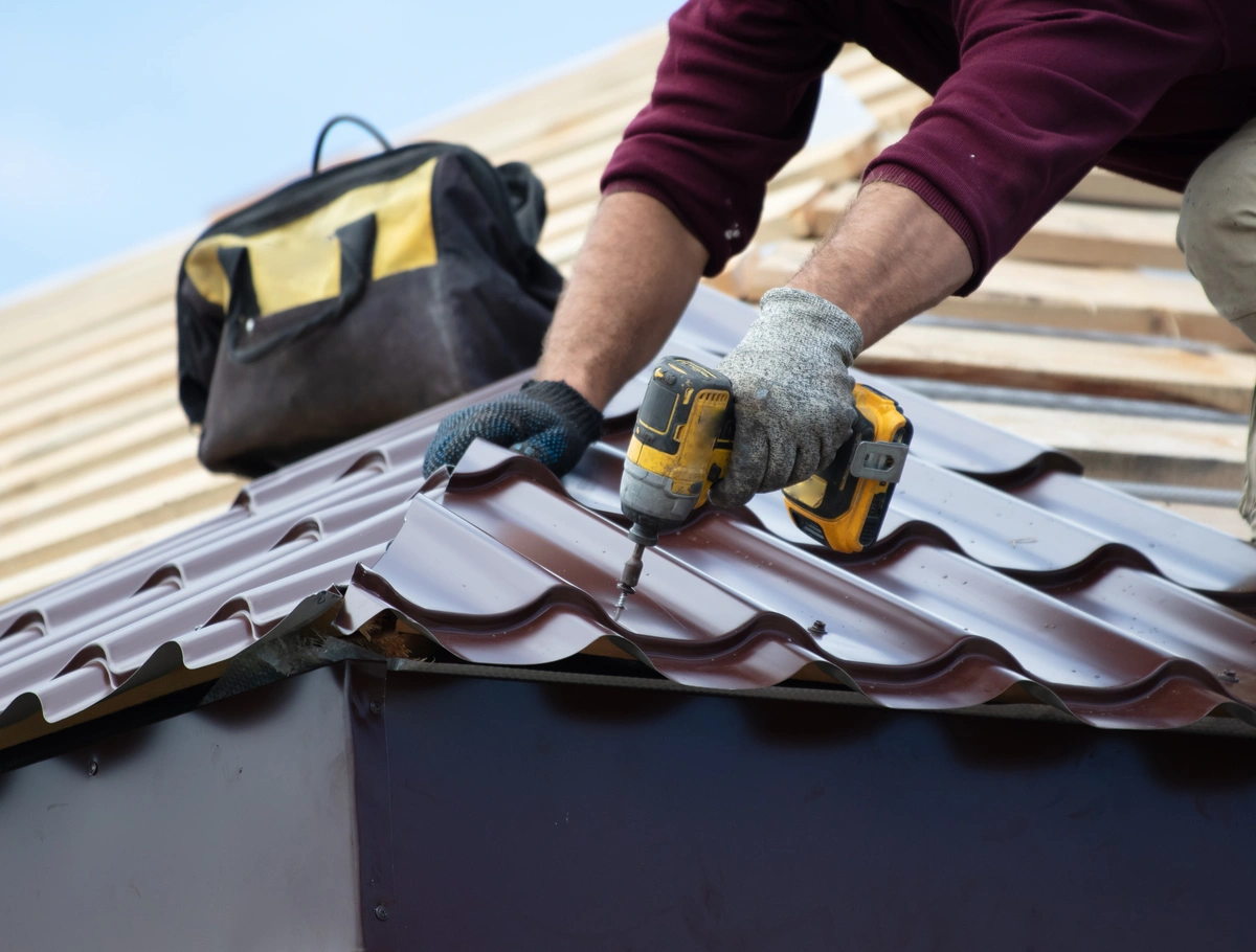 worker using nail gun to install metal sheets