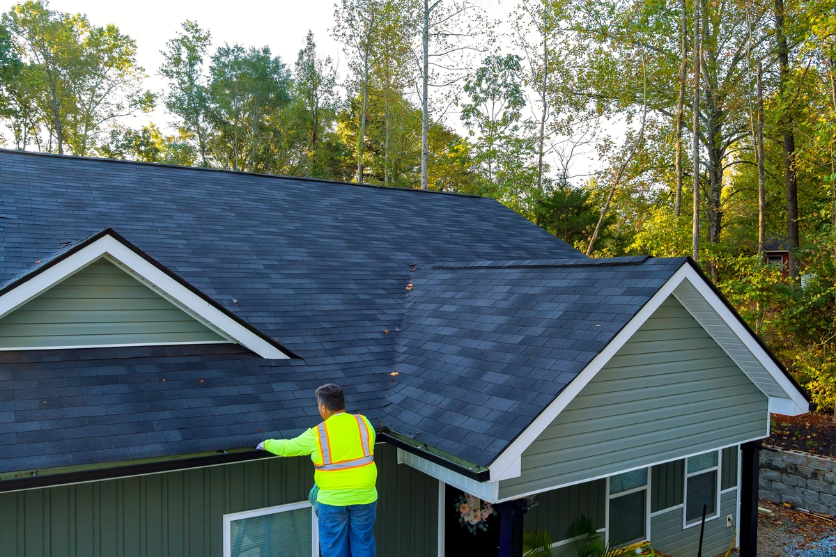 man safely cleaning house roof