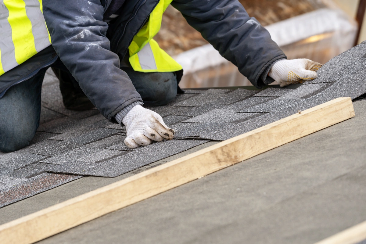 close up to worker installing new shingles