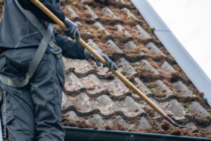 a worker removing roofmoss