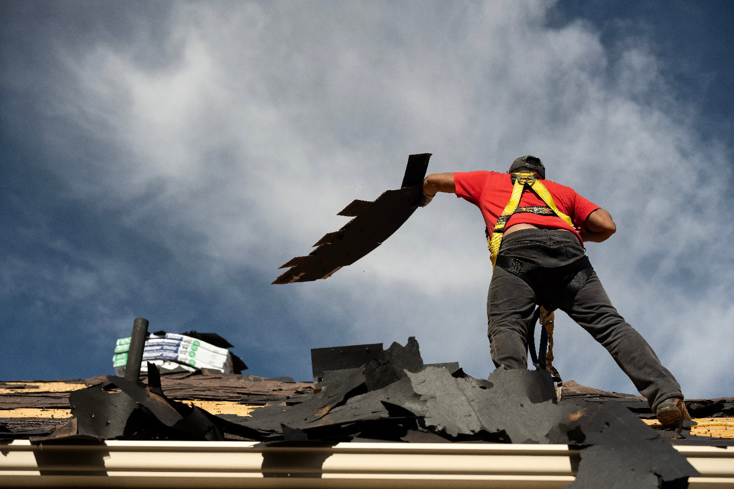 A worker removing black end shingles