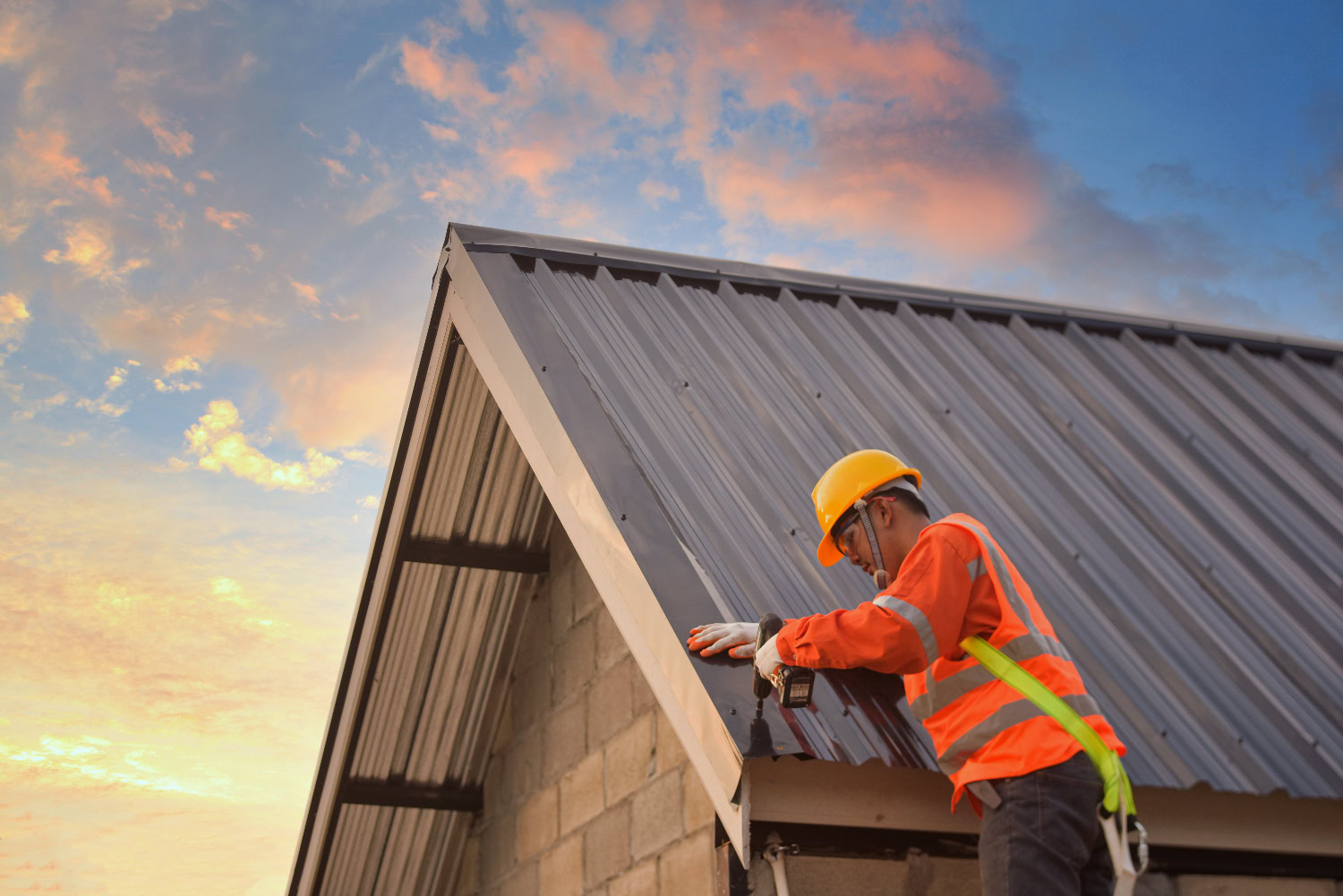 worker drilling in final bolts of a metal roof
