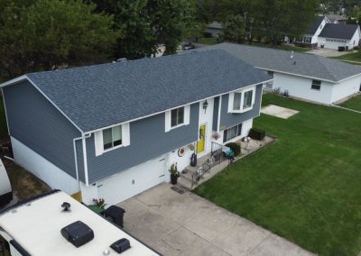 A split-level house with blue siding, a yellow front door, and an attached garage, surrounded by grass lawns and neighboring houses.